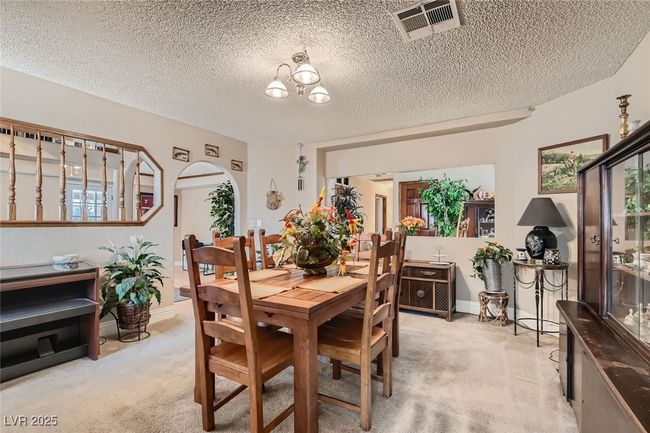 Dining room with light carpet, visible vents, arched walkways, and a textured ceiling | Image 10