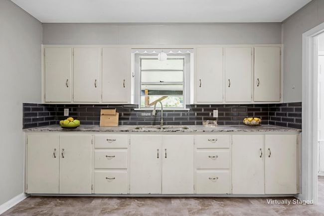 Kitchen with tasteful backsplash, light stone countertops, and white cabinetry | Image 6
