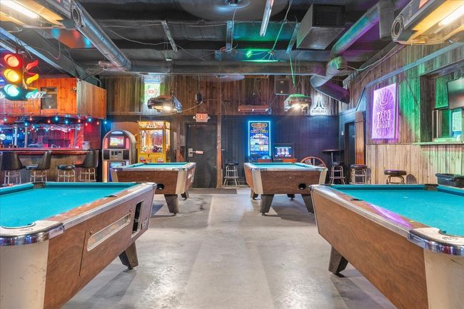 Game room featuring billiards, concrete flooring, wood walls, and a bar | Image 7