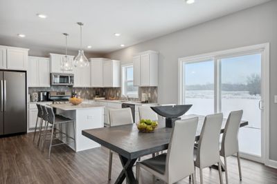 (*Photo of decorated model, actual homes finishes will vary) The open and bright modern kitchen is anchored by a large center island and is surrounded by expansive countertops providing true eat in and entertaining capabilities. | Image 3