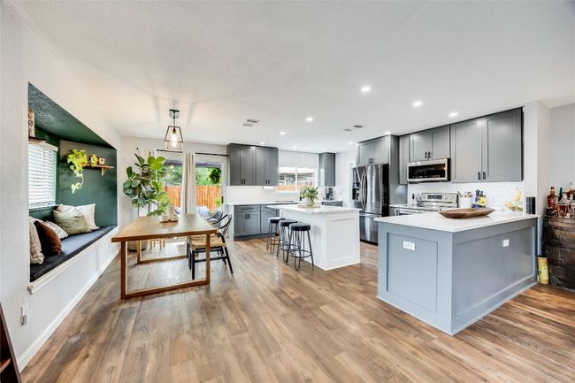 Kitchen featuring stainless steel appliances, gray cabinets, light countertops, a kitchen bar, and light wood finished floors | Image 18