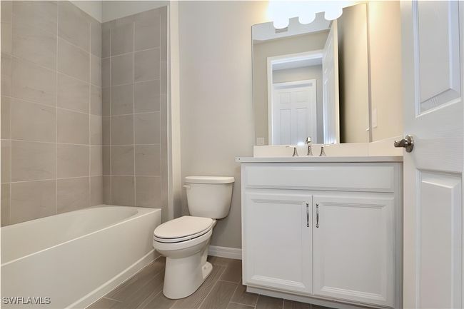 Bathroom featuring toilet, vanity, baseboards, and bathing tub / shower combination | Image 10