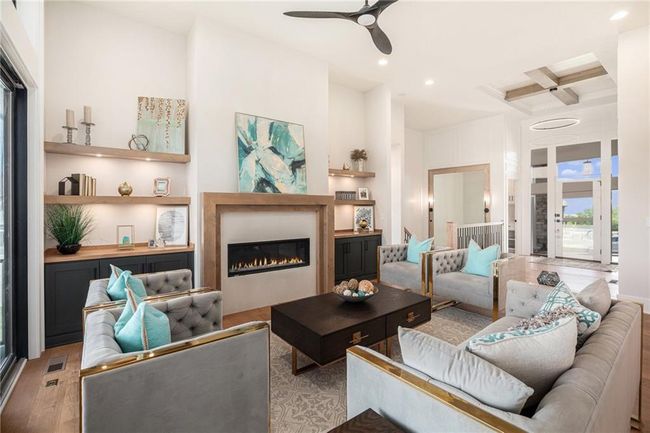 Living room featuring wood finished floors, coffered ceiling, a ceiling fan, recessed lighting, and a glass covered fireplace | Image 5