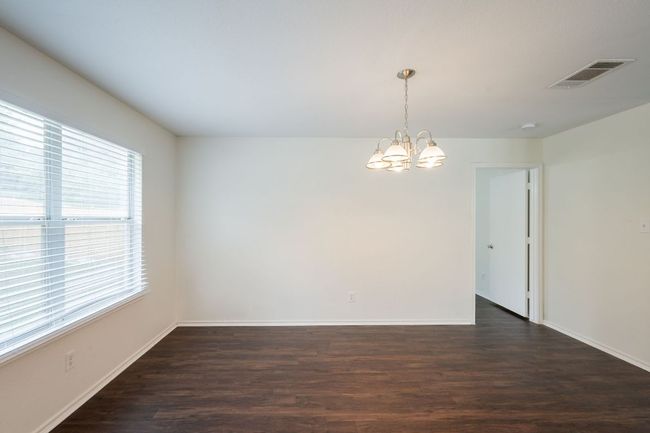 Dining area with a chandelier, dark wood-type flooring, and baseboards | Image 13