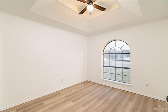 Unfurnished room featuring a ceiling fan, a raised ceiling, light wood-style flooring, and baseboards | Image 8