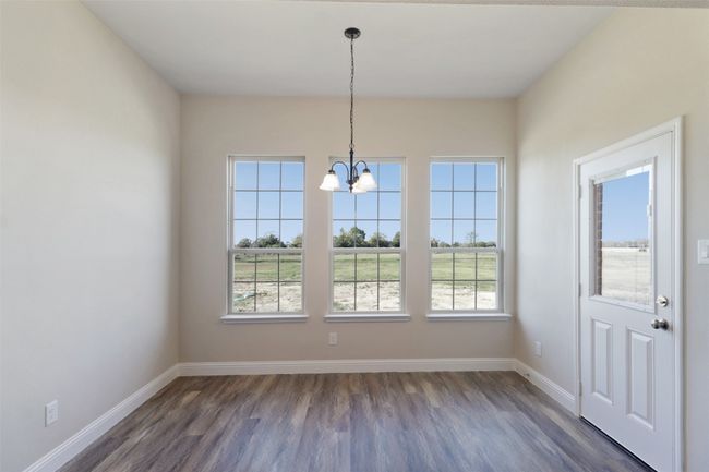 Unfurnished dining area with dark wood-type flooring, an inviting chandelier, and baseboards | Image 7