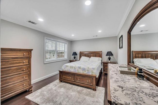 Bedroom with baseboards, visible vents, crown molding, and dark wood finished floors | Image 11