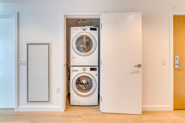 Laundry room with laundry area, light wood-style flooring, baseboards, and stacked washer / drying machine | Image 11