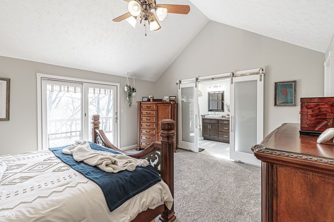 bedroom featuring a barn door, ensuite bathroom, ceiling fan, light carpet, and access to outside | Image 24