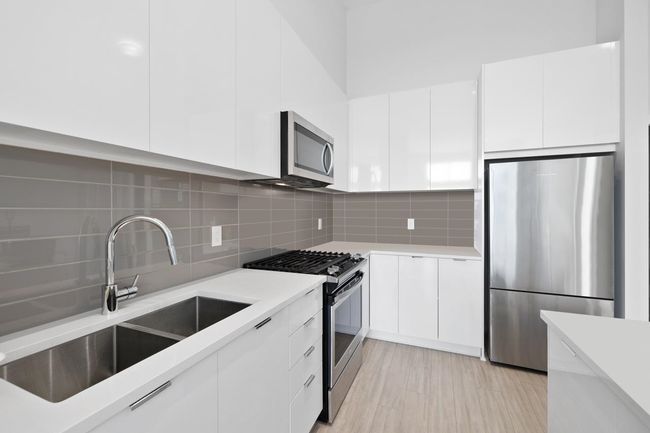 Kitchen featuring modern cabinets, white cabinetry, stainless steel appliances, and a sink | Image 11