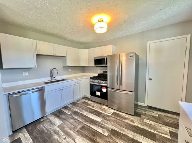 kitchen with a sink, light countertops, dark wood-type flooring, and stainless steel appliances | Image 7