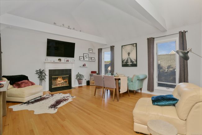 The living room has a vaulted ceiling, beams, and hardwood floors. | Image 4