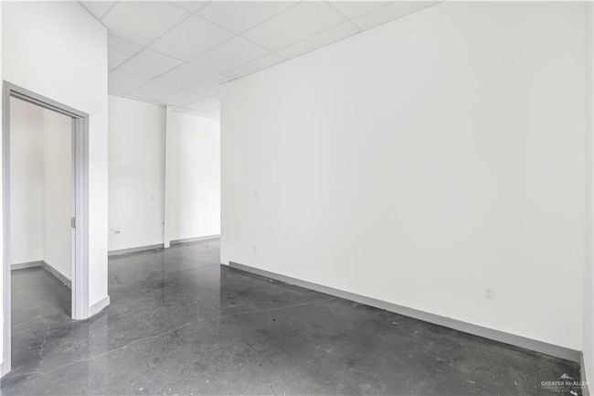 Unfurnished room with concrete floors, baseboards, and a drop ceiling | Image 35