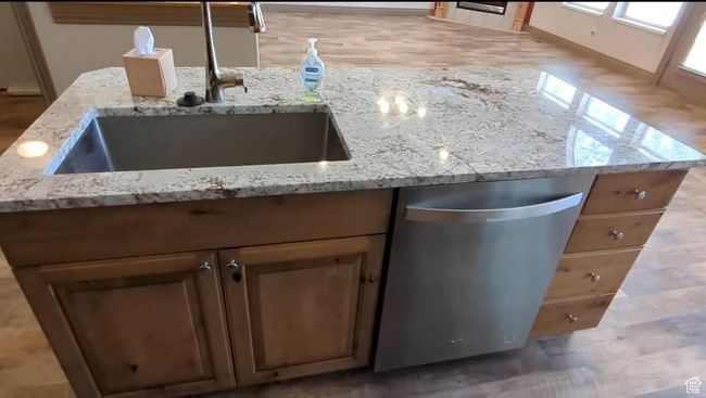 Kitchen view of a sink, dishwasher, light stone counters, and wood finished floors | Image 11