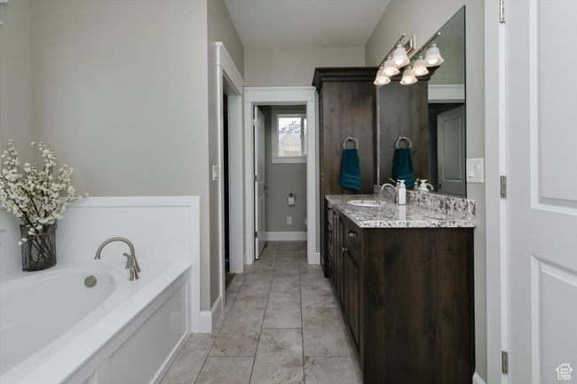 Bathroom with double vanity, a garden tub, baseboards, and a sink | Image 43