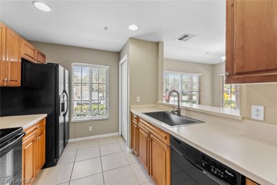 Kitchen with a wealth of natural light, sink, black appliances, and light tile flooring | Image 2