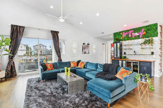Living area featuring wood finished floors, beverage cooler, recessed lighting, a ceiling fan, and a bar | Image 8
