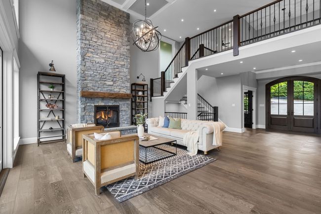 Living area with a towering ceiling, stairs, wood finished floors, baseboards, and a fireplace | Image 9