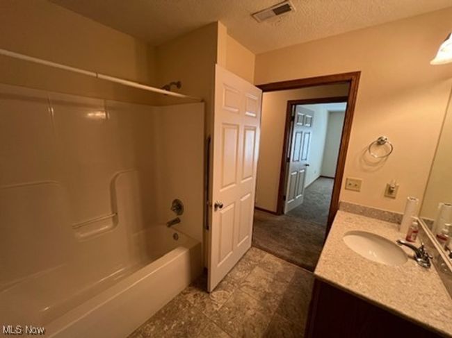 Bathroom featuring vanity, tub / shower combination, and a textured ceiling | Image 23
