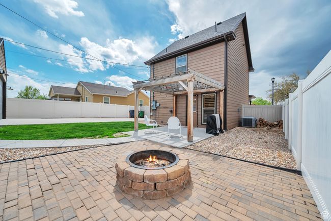 Back of house featuring a patio, a pergola, central AC unit, a fenced backyard, and a fire pit | Image 21