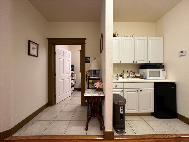 Kitchen featuring white microwave, refrigerator, white cabinetry, and light tile patterned flooring | Image 16