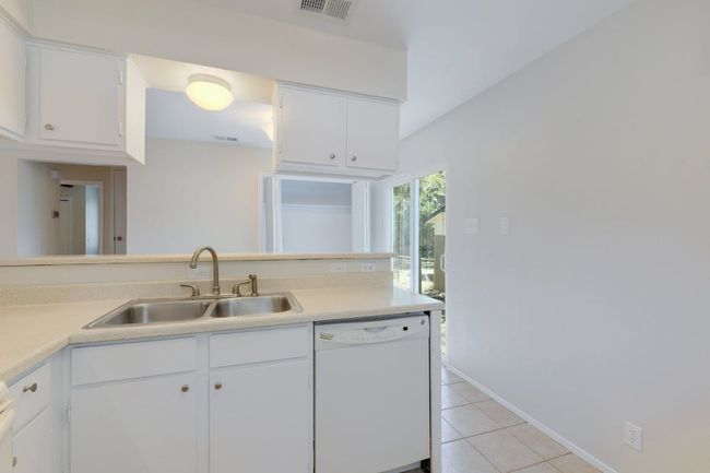 Kitchen with dishwasher, a sink, light tile patterned flooring, light countertops, and white cabinetry | Image 5