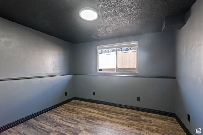 Empty room with baseboards, visible vents, wood finished floors, and a textured ceiling | Image 24