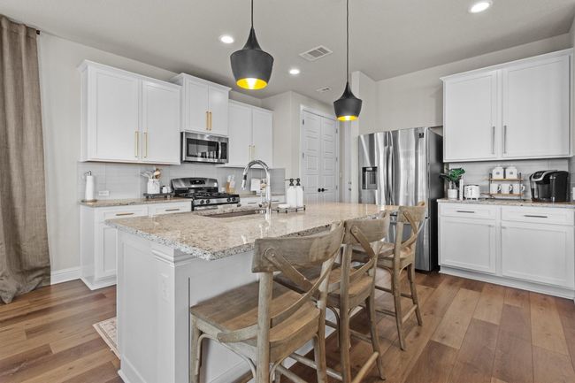 Kitchen featuring backsplash, wood-type flooring, appliances with stainless steel finishes, light stone counters, and recessed lighting | Image 17