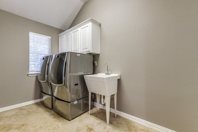 Laundry area featuring separate washer and dryer, cabinet space, and baseboards | Image 16