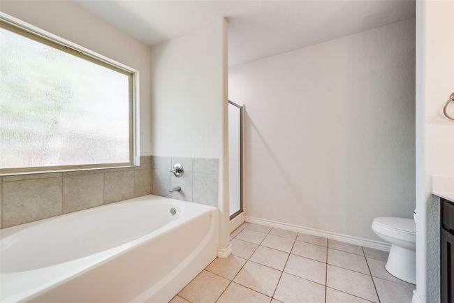 Full bath with vanity, baseboards, tile patterned floors, toilet, and a bath | Image 25