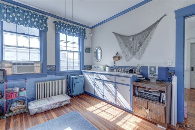 Kitchen with cooling unit, light countertops, crown molding, light wood finished floors, and radiator heating unit | Image 22