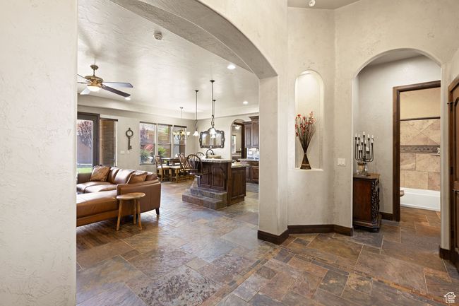 Living room featuring arched walkways, stone tile floors, ceiling fan, and a textured wall | Image 46