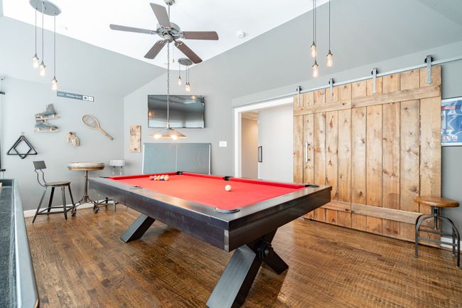 Playroom with a barn door, vaulted ceiling, wood finished floors, billiards, and ceiling fan | Image 28