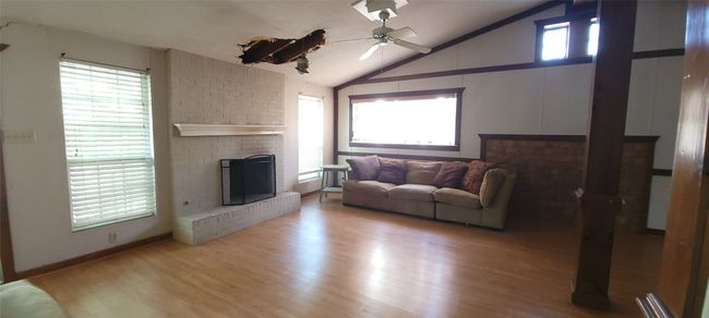 Living room with a ceiling fan, a fireplace, wood finished floors, and high vaulted ceiling | Image 4