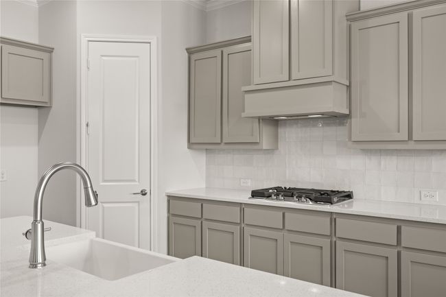 Kitchen featuring gray cabinetry, stainless steel gas stovetop, a sink, ornamental molding, and decorative backsplash | Image 7