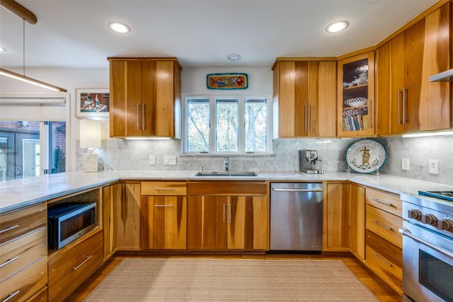 Kitchen featuring pendant lighting, sink, light hardwood / wood-style flooring, backsplash, and stainless steel appliances | Image 14