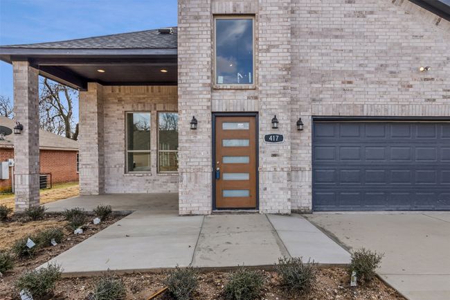 View of exterior entry with roof with shingles, brick siding, and a garage | Image 9