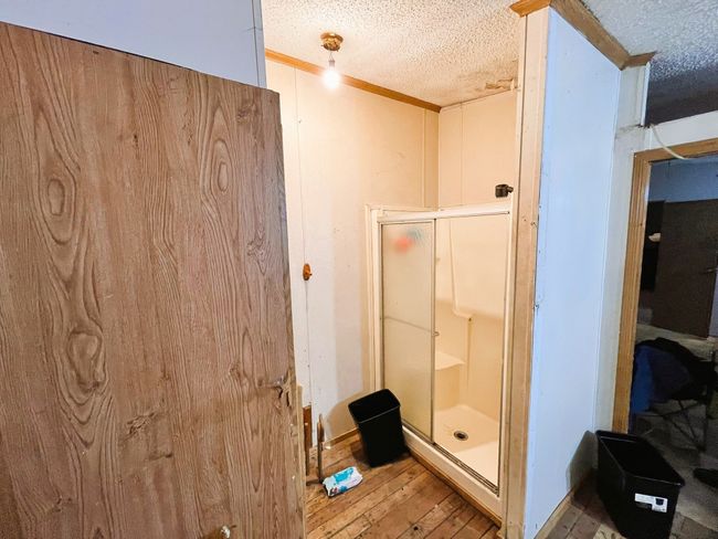 Bathroom featuring hardwood / wood-style flooring, a shower stall, a textured ceiling, and ornamental molding | Image 17