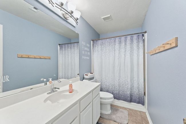 Full bath with vanity, shower / tub combo with curtain, a textured ceiling, and tile patterned flooring | Image 27