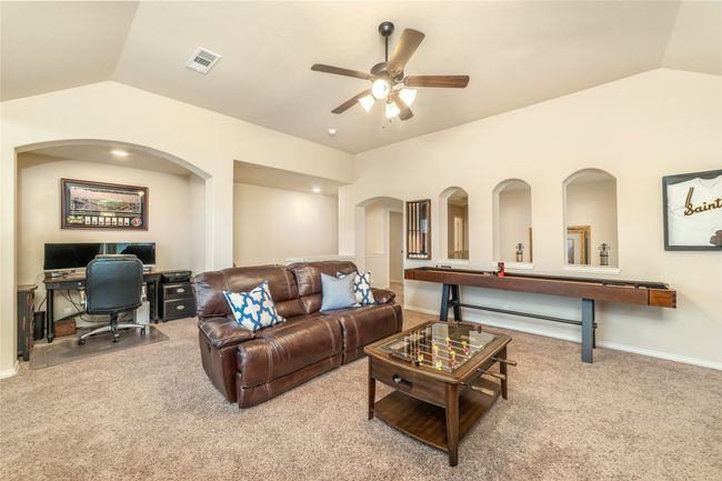 Carpeted living area featuring vaulted ceiling, an office area, ceiling fan, arched walkways, and baseboards | Image 24