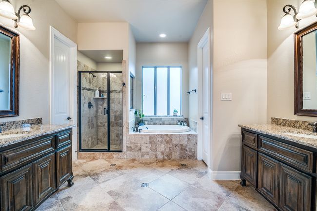 Enjoy a relaxing bath in the cozy-sized jetted tub. The separate shower space is fully tiled and accommodates tall bathers. It is generously lighted with recessed lighting. There is a very large walk-in closet located in the ensuite. | Image 23