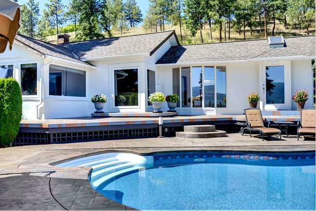 Back of property featuring a deck, stucco siding, a chimney, and an outdoor pool | Image 28
