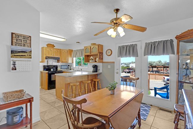 Dining room with light tile patterned flooring, ceiling fan, and a textured ceiling | Image 8