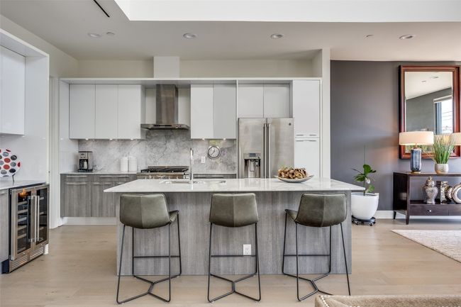 Kitchen featuring beverage cooler, a kitchen breakfast bar, wall chimney range hood, modern cabinets, and stainless steel refrigerator with ice dispenser | Image 9