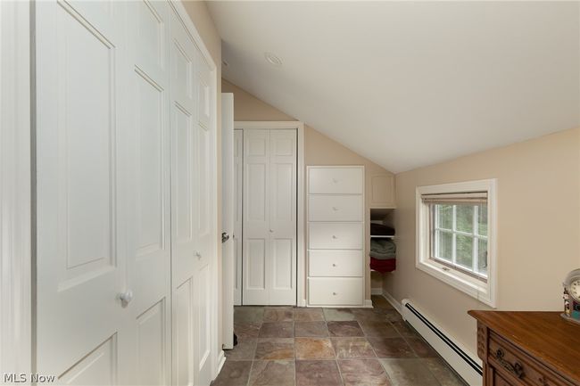 Corridor with vaulted ceiling, baseboard heating, and dark tile floors | Image 42