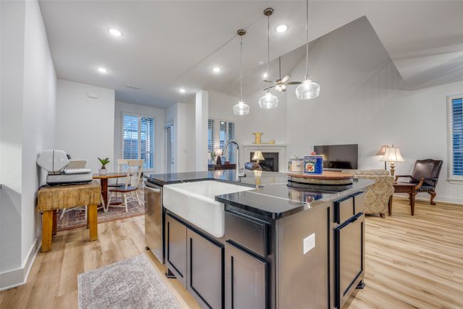 Kitchen featuring light wood-type flooring, a glass covered fireplace, dishwasher, a sink, and open floor plan | Image 9
