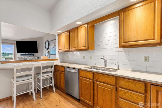 Kitchen with loads of counter space, cabinetry and convenient bar with views to the water across the living room | Image 17