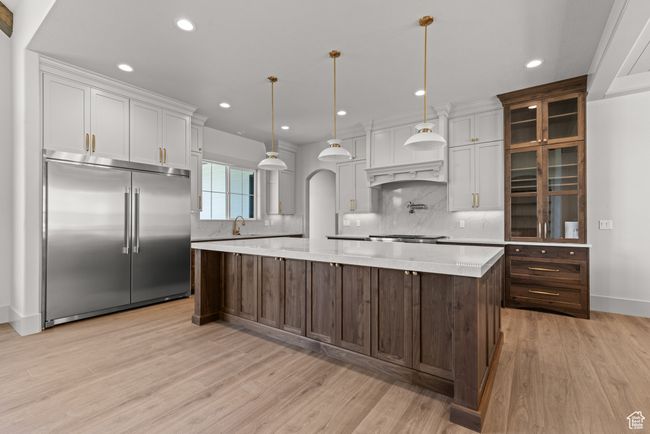 Kitchen with built in fridge, decorative backsplash, light wood-style floors, recessed lighting, and a large island | Image 9