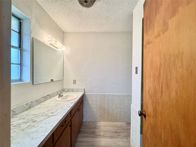 Bathroom with vanity, hardwood / wood-style floors, a textured ceiling, and a wealth of natural light | Image 25
