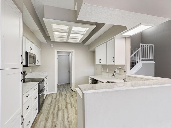 Kitchen featuring a sink, light stone counters, light wood-style floors, and appliances with stainless steel finishes | Image 10